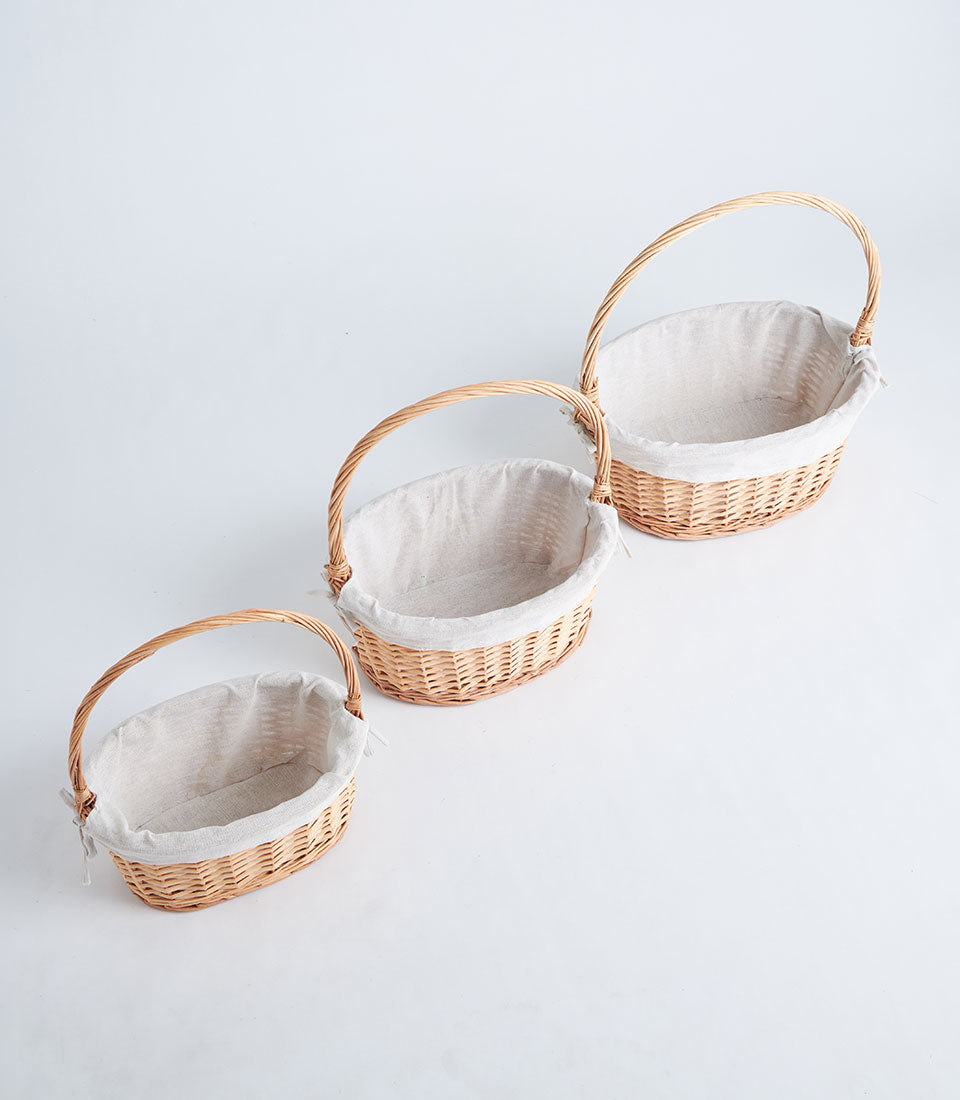 Set of three oval wicker gift baskets with beige fabric liners and woven handles