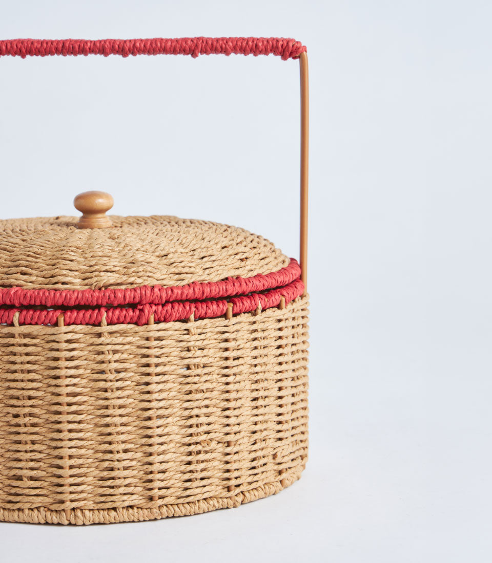 Natural woven basket with red cord trim and wooden handle, perfect for artisan gift presentation