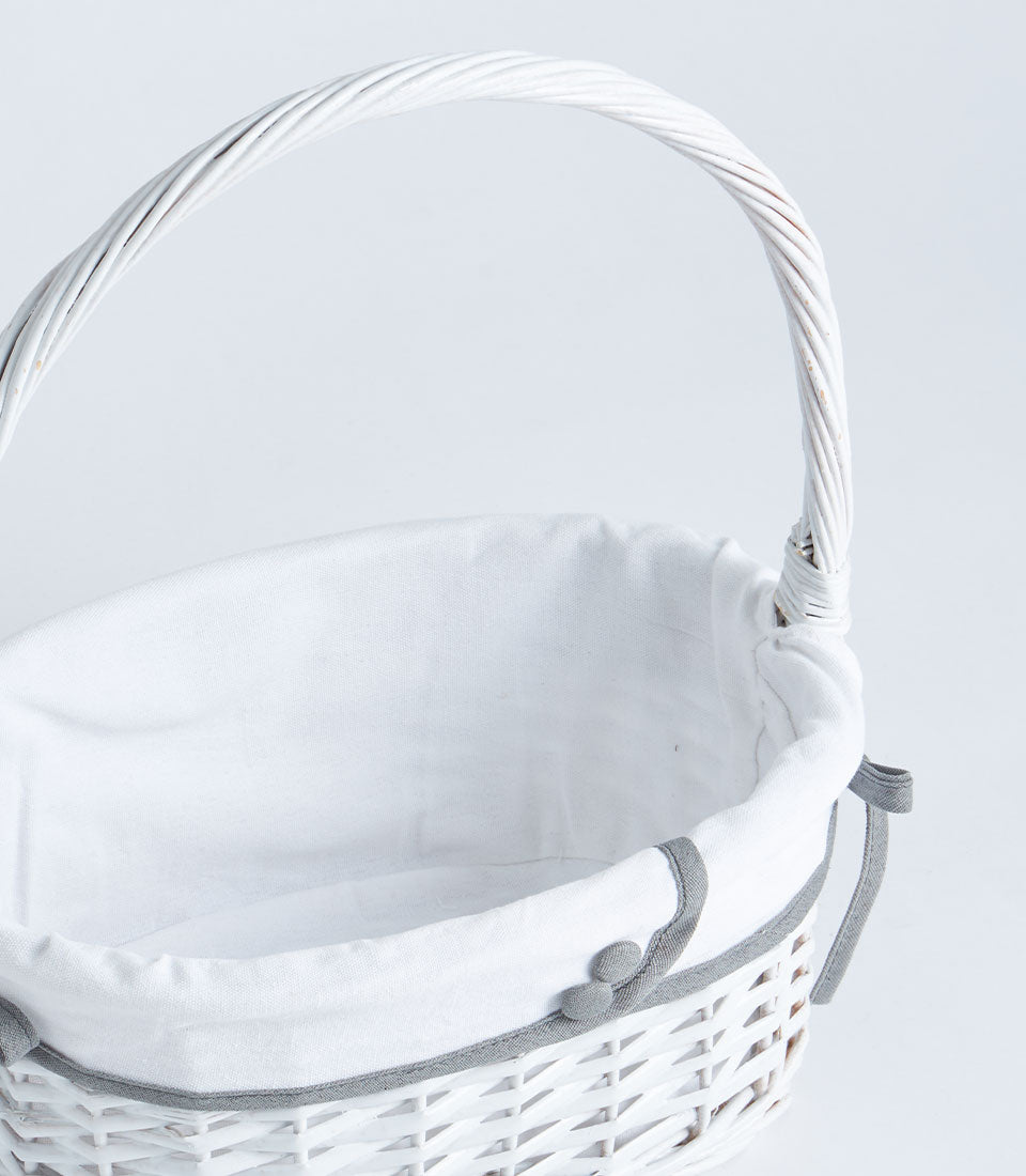 Handwoven white wicker basket with tall handle and grey-trimmed fabric lining