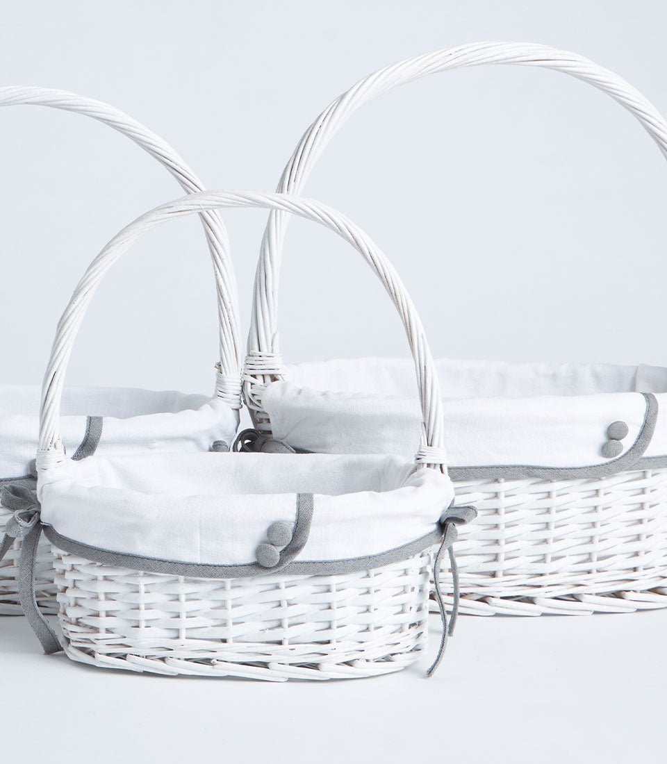Handwoven white wicker baskets with tall handles and removable fabric liners in three sizes