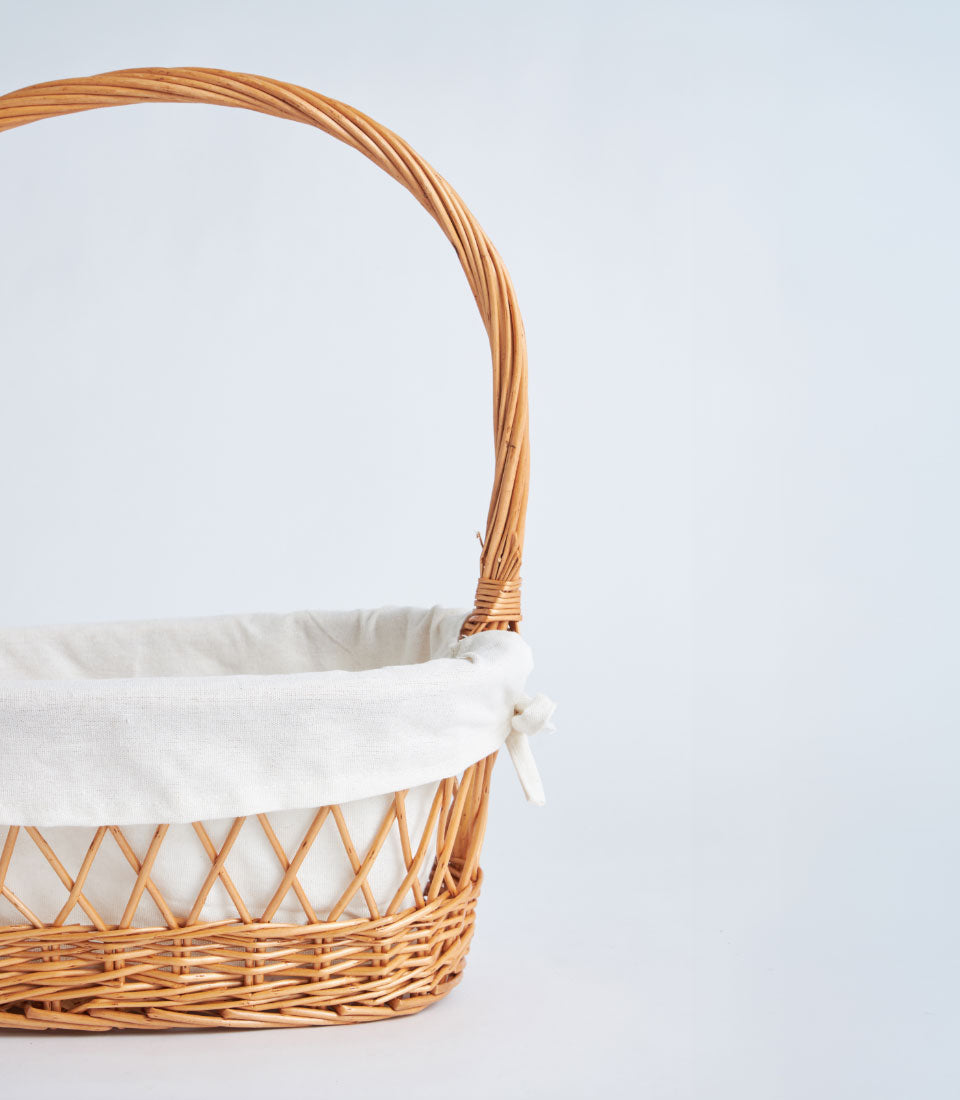 Natural wicker oval basket with lattice weave, white fabric lining and arched handle for luxury gifting