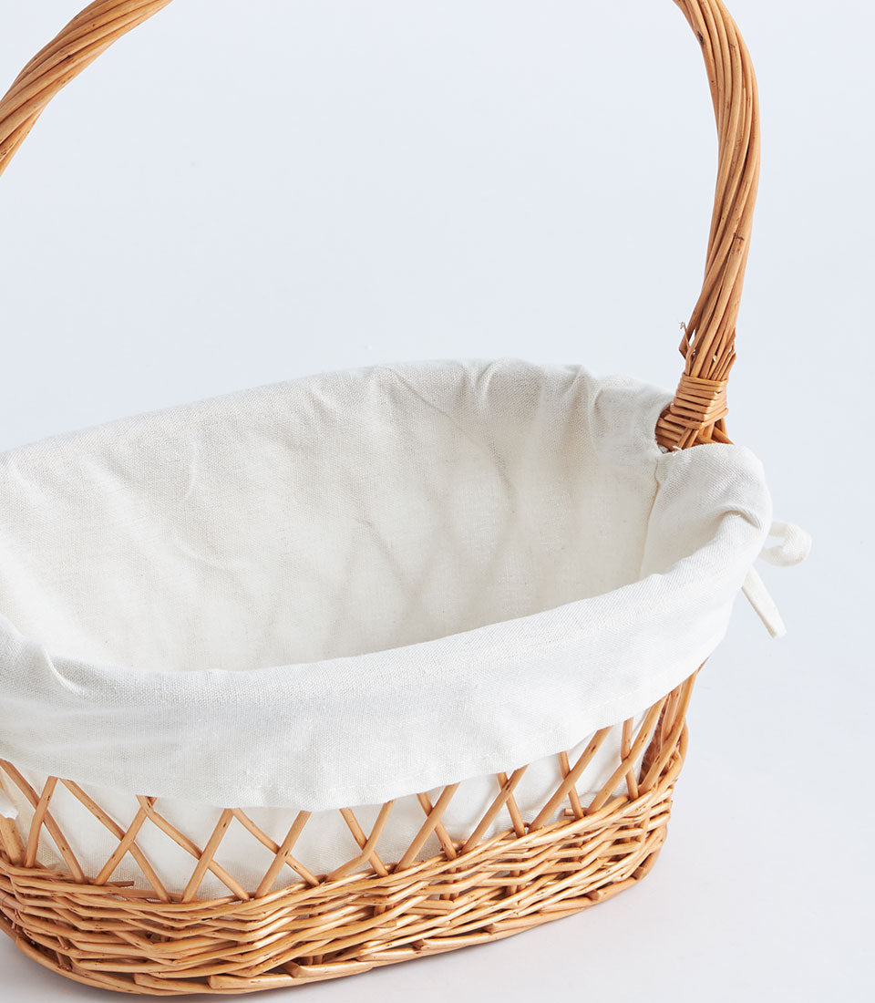 Natural wicker oval basket with white fabric lining and twisted handle for luxury gifting