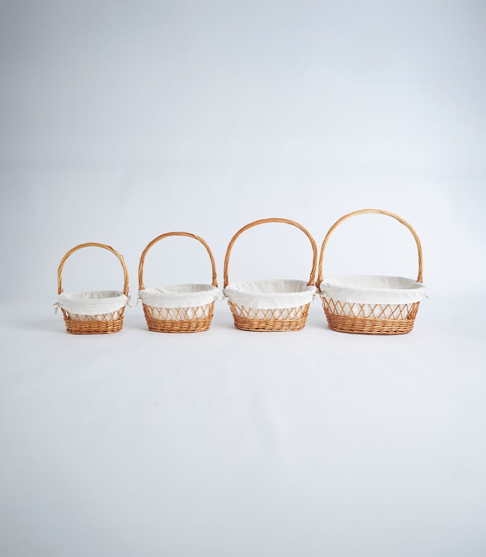 Nested wicker baskets with white fabric liners and handles, natural weave detail for gift hampers
