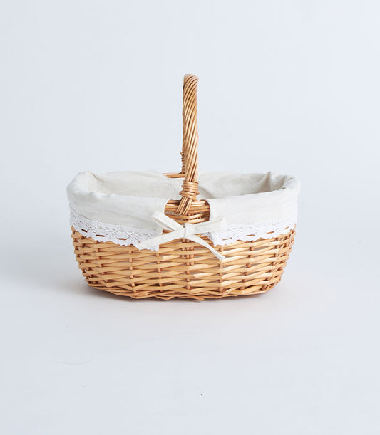Handwoven oval wicker basket with cream lace-trimmed fabric liner and white bow