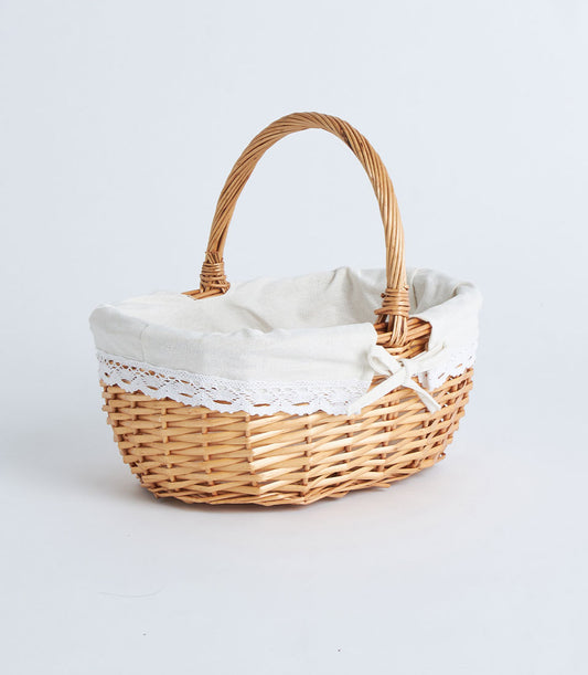 Light brown woven wicker oval basket with cream lace-trimmed fabric liner and arched handle