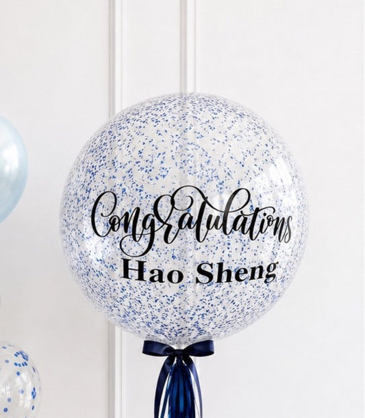 Large clear balloon filled with blue confetti, tied with navy ribbon bow, displaying "Congratulations Hao Sheng" text in elegant script.