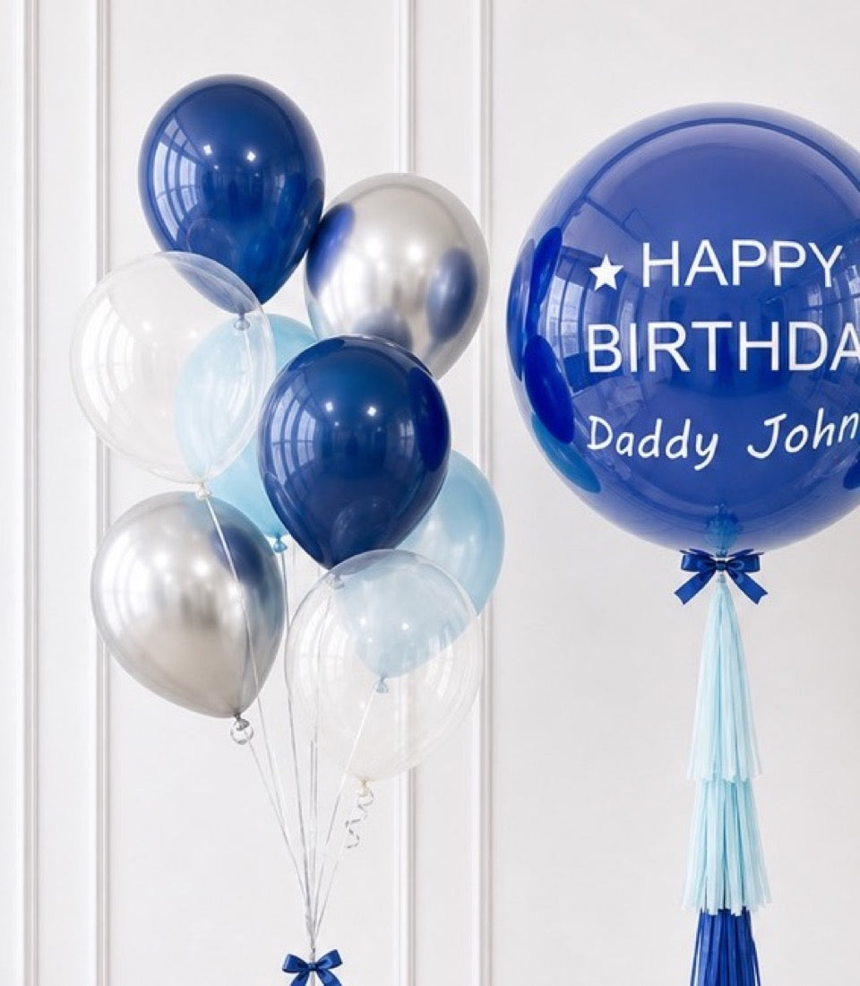 Blue and silver metallic balloons with a large personalized "Happy Birthday Daddy John" bubble balloon featuring a blue ribbon tassel.