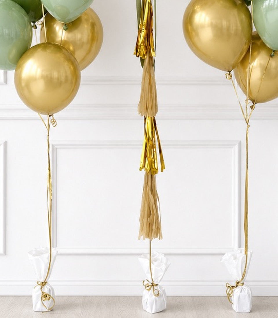 Gold and sage balloon bouquets with gold tassel fringe and white weighted bases, elegant party decoration set.