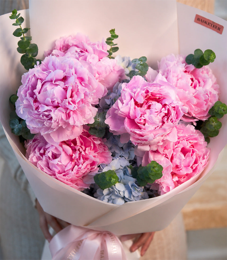 A luxurious Flowers by Basketeer bouquet featuring vibrant pink peonies, delicate blue hydrange
