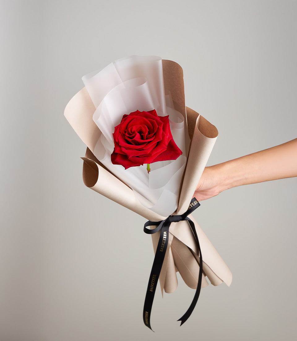 Luxurious single red rose, elegantly wrapped in kraft and white tissue, tied with