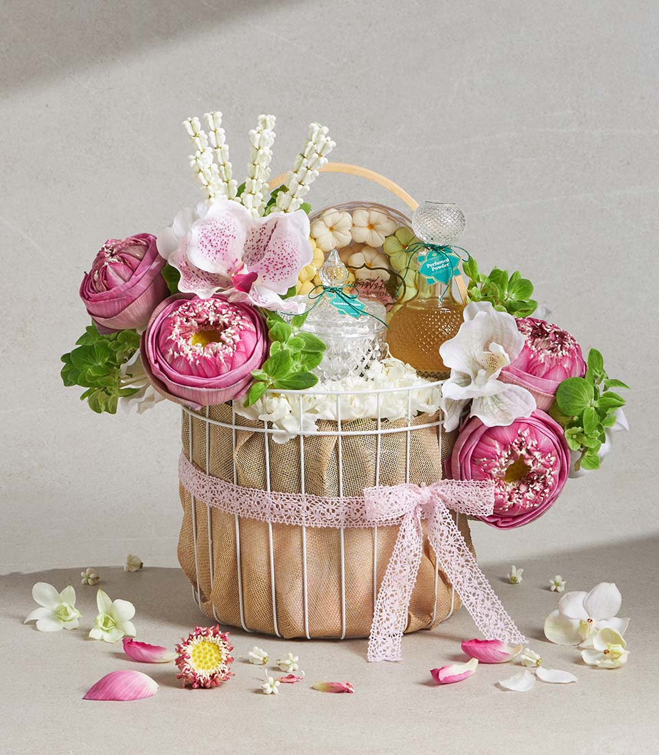 White wire gift basket with pink lotus, white orchids, perfumed powder, and flower-shaped cookies