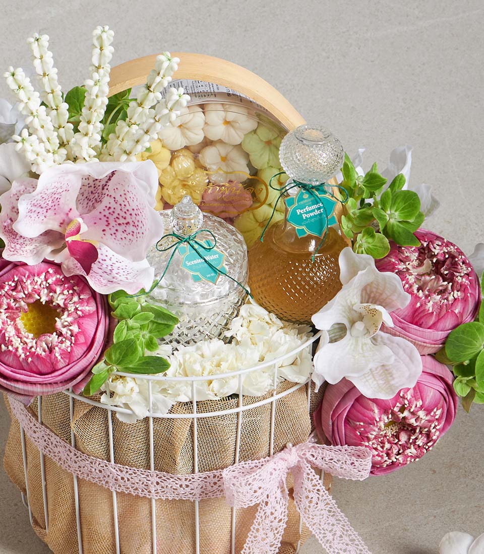 White wire gift basket with pink orchids, white flowers, pink lotus blossoms, scented water, perfumed powder, and