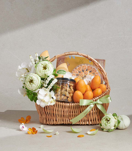 Premium wicker gift basket with white lotus and orchid flowers, gourmet treats, and heart-shaped cookies
