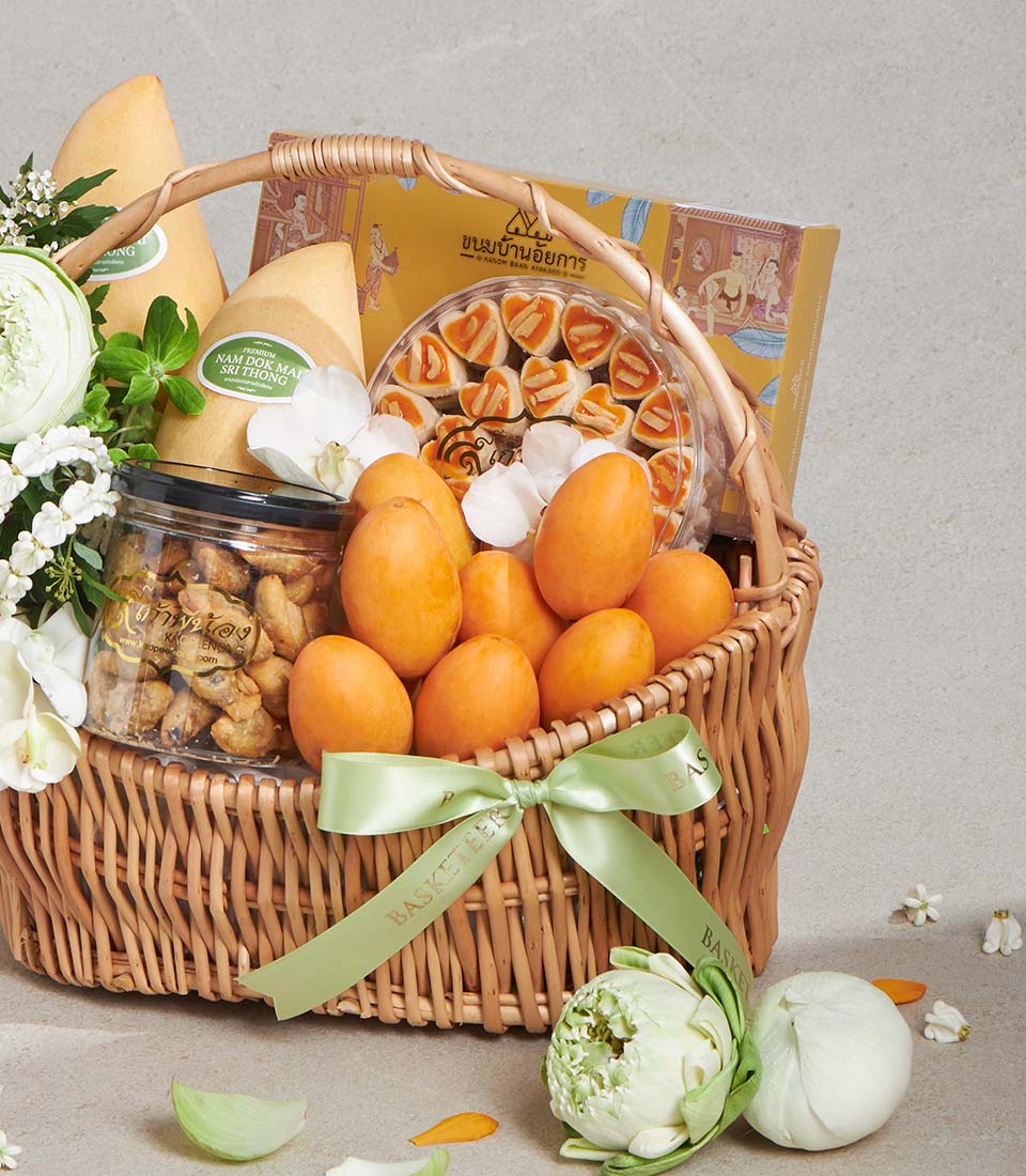 Premium wicker gift basket with Nam Dok Mai mangoes, cashews, cookies, orange fruits, and white orchids