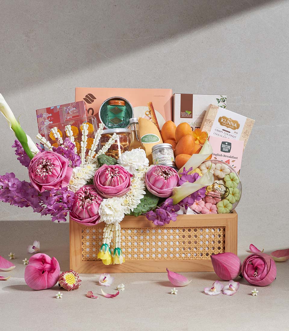 Luxury gift basket with fresh pink lotus flowers, Thai garland, gourmet treats, and artisan chocolates in wooden rattan box