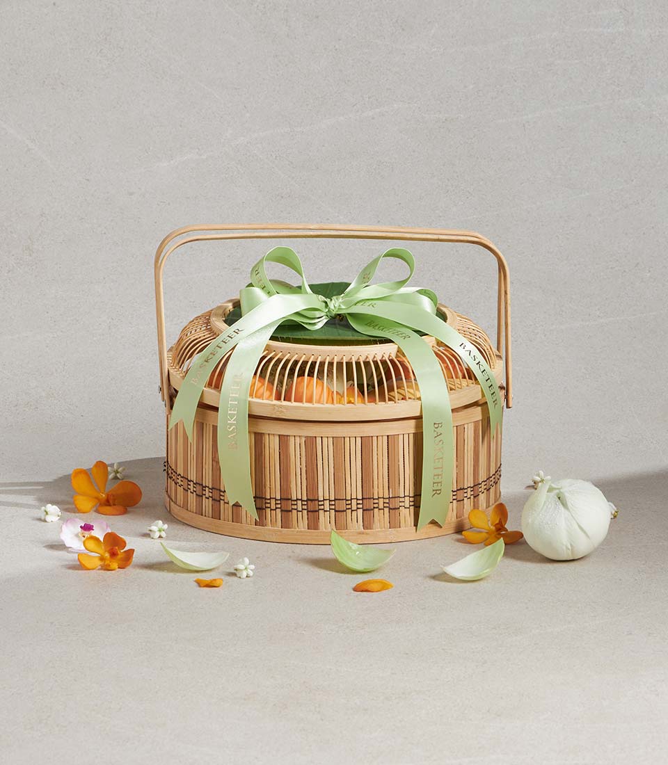 Songkran scented bliss gift basket with two-tiered bamboo design, orange fruits, and fresh orchid flowers