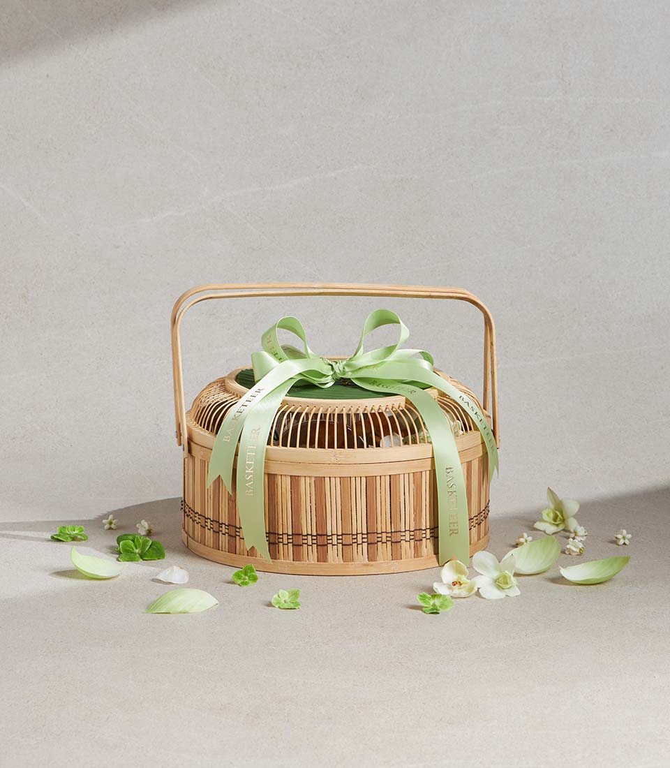 Tiered bamboo gift basket with satin ribbon and scattered white flowers