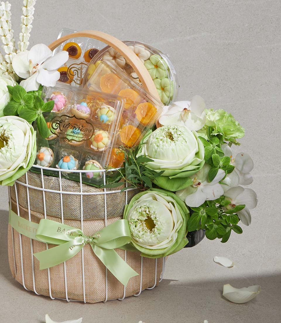 White wire gift basket with lotus flowers, orchids, and gourmet pastries in pastel hues
