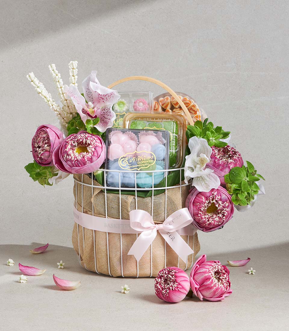 White wire gift basket with pink lotus blossoms, orchids, jasmine, artisan sweets and pastries for Songkran celebration