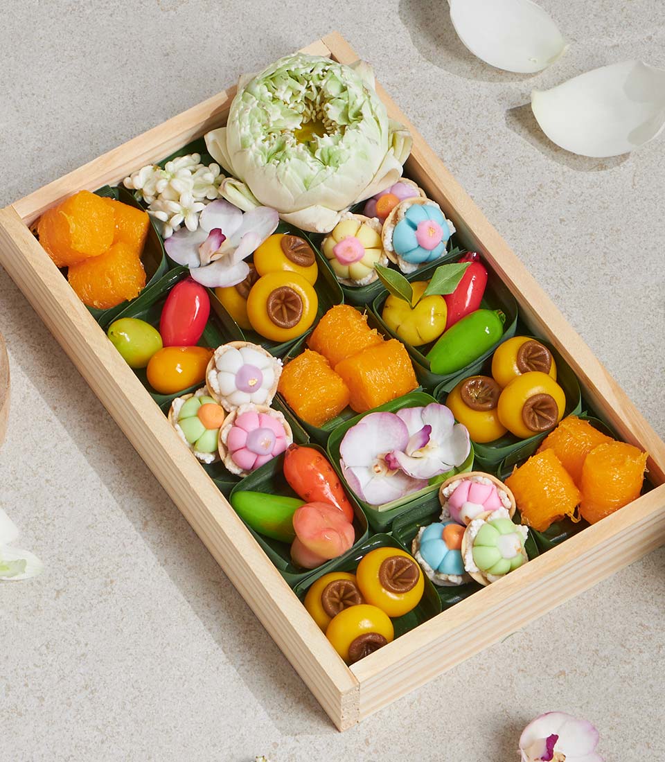 Thai lotus sweet dessert gift box with jasmine, orchids, and colorful traditional sweets in wooden compartments