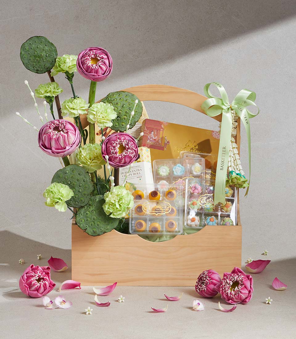 Wooden gift basket with Thai sweets, golden packaging, and pink lotus flowers with green carnations for Songkran gifting