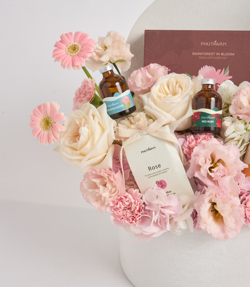 Phutawan luxury gift set with pink and cream flowers, amber glass bottles, rose product packaging, and brown branded box on white surface.