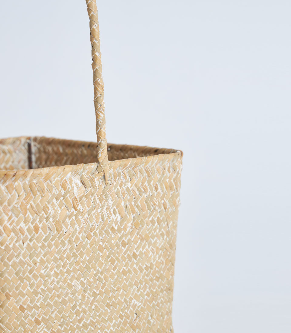 Light natural woven straw basket with braided handle, handcrafted with rustic charm