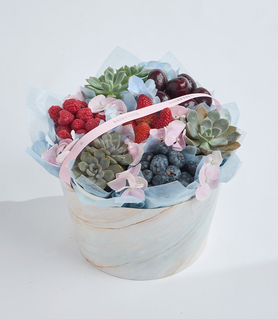 # Alt Text

Elegant gift arrangement featuring fresh berries, succulents, and pink flowers in a white marble box with blue tissue wrapping and pink ribbon.
