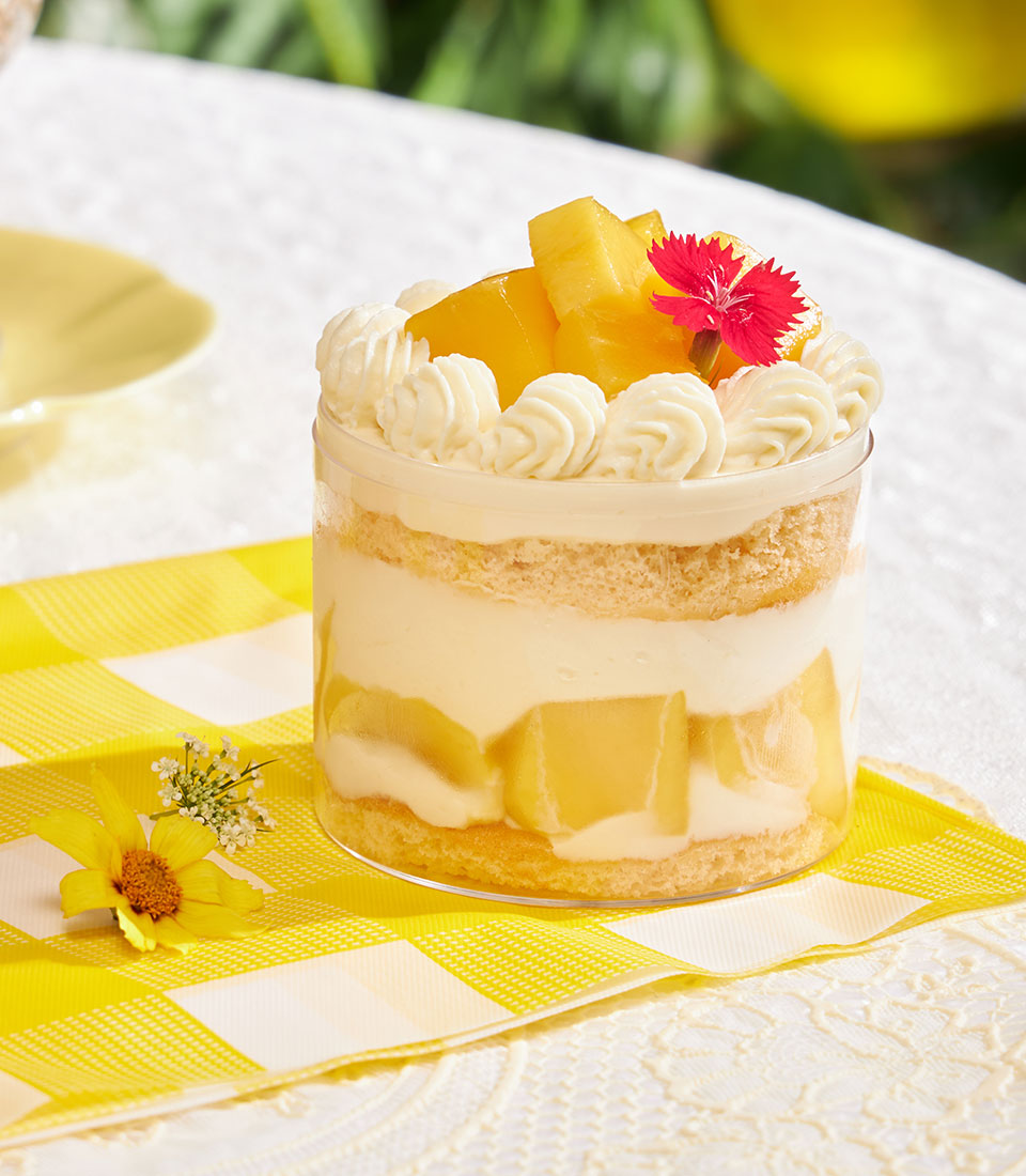 Mini chiffon cake with fresh cream, pineapple, and fruit in clear cylindrical container