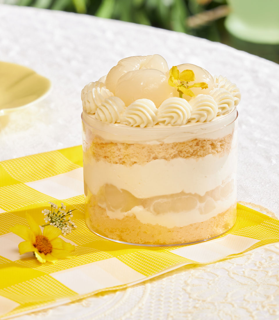 Mini chiffon cake with fresh cream, lychee, and piped rosettes in clear cup dessert