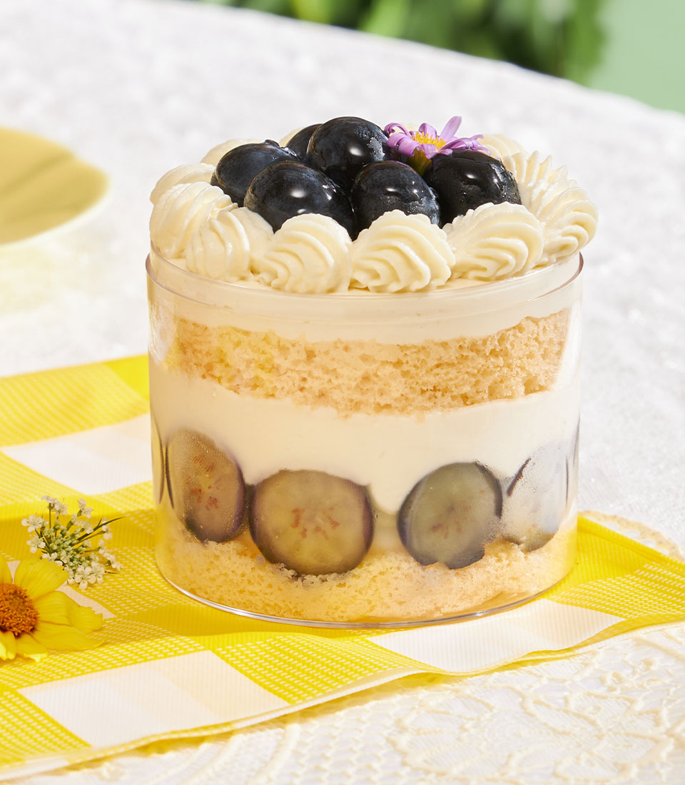 Layered chiffon cake with fresh cream, grapes, and blueberries in clear cylindrical container