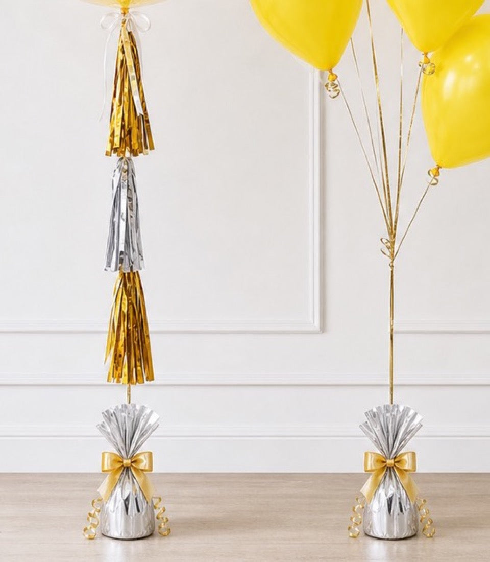# Alt Text

Yellow balloons with gold and silver tassel garlands and matching balloon weights on white wall backdrop.