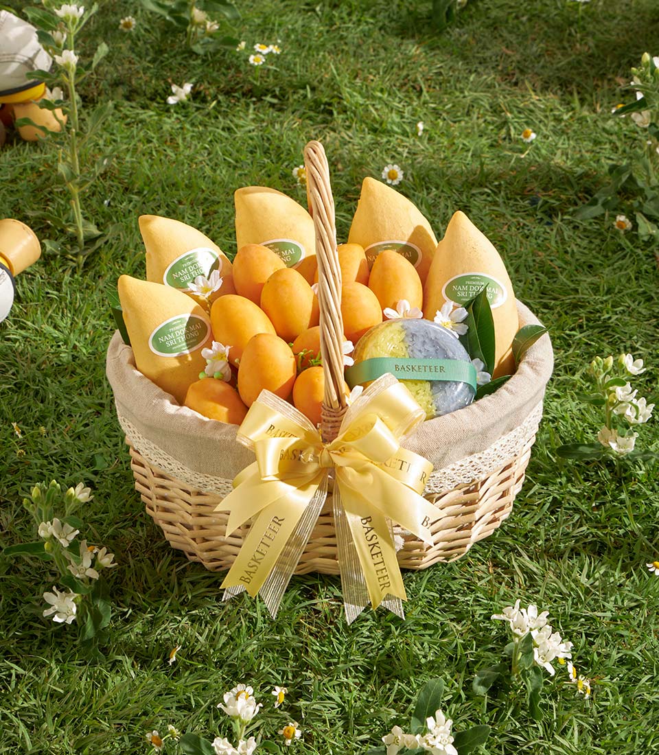 Premium Thai mango and mayongchid gift basket with yellow satin bow on garden backdrop
