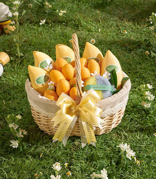 Premium Thai mango and mayongchid gift basket with yellow satin bow on garden backdrop