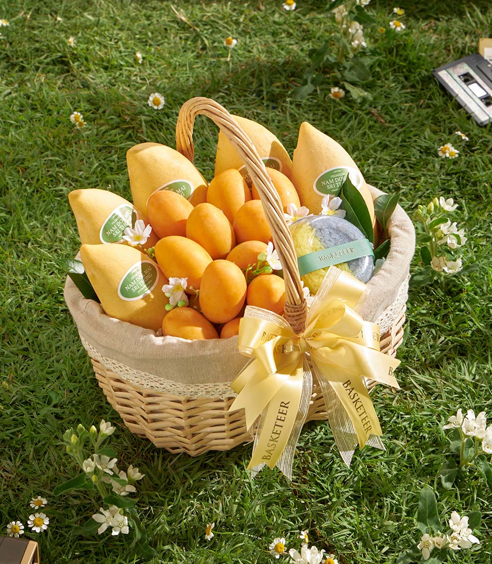 Woven wicker gift basket with premium Nam Dok Mai mangoes, orange fruits, and bath bomb with golden ribbon