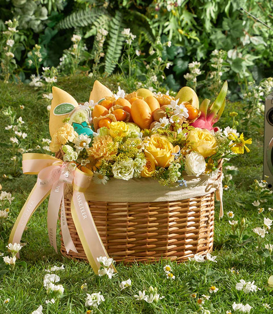 Woven wicker fruit basket with fresh mangoes, dragon fruit, and yellow roses, tied with pale yellow ribbon