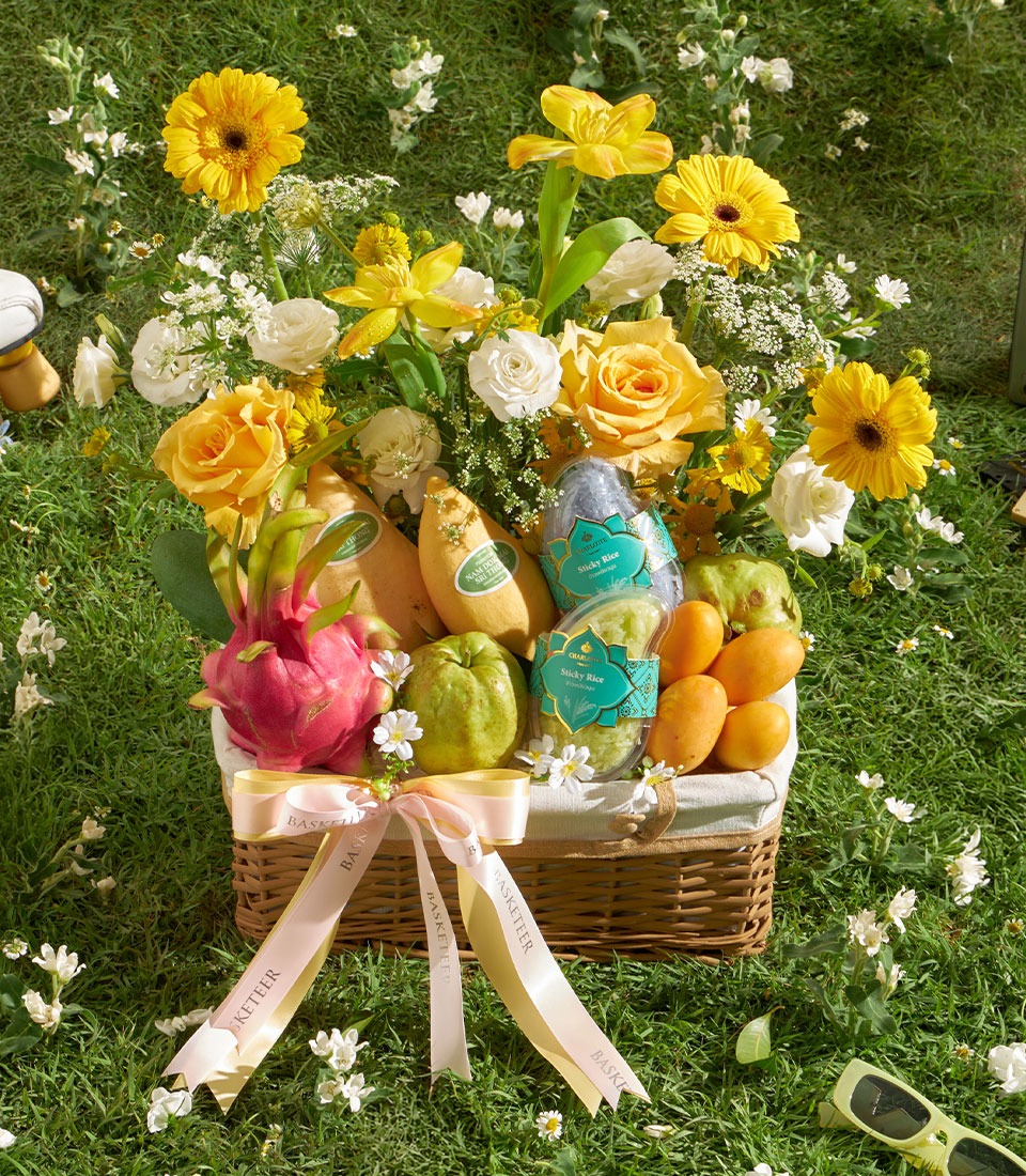 Summer fruit and flower gift basket with fresh mangoes, dragon fruit, guavas, yellow and white roses, and gerbera daisies