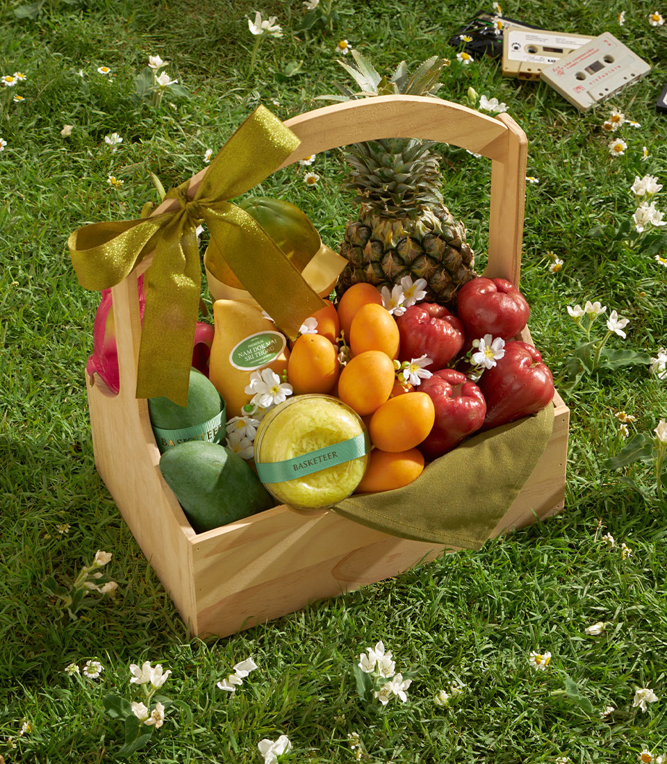 Premium tropical fruit gift basket with mango, pineapple, rose apples and gourmet goods, tied with olive ribbon