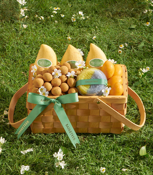 Woven gift basket filled with fresh yellow mangoes, golden longans, and artisan mayongchid, adorned with green ribbon bow
