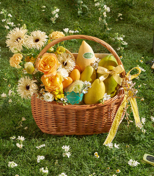 Wicker gift basket with golden mango, papayas, pears, sticky rice, and yellow-orange fresh flowers