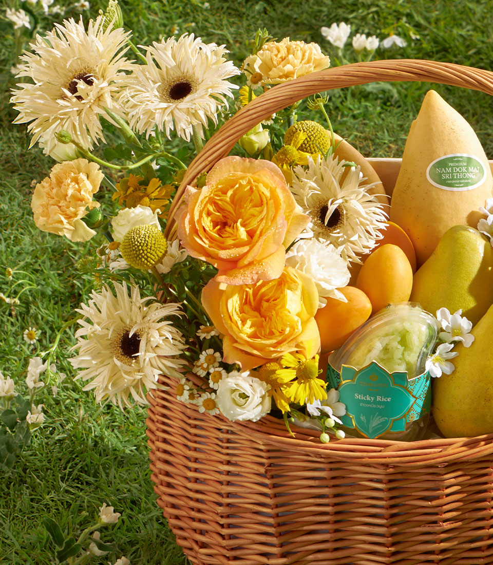 Golden mango gift basket with yellow roses, gerbera daisies, fresh fruit, and sticky rice
