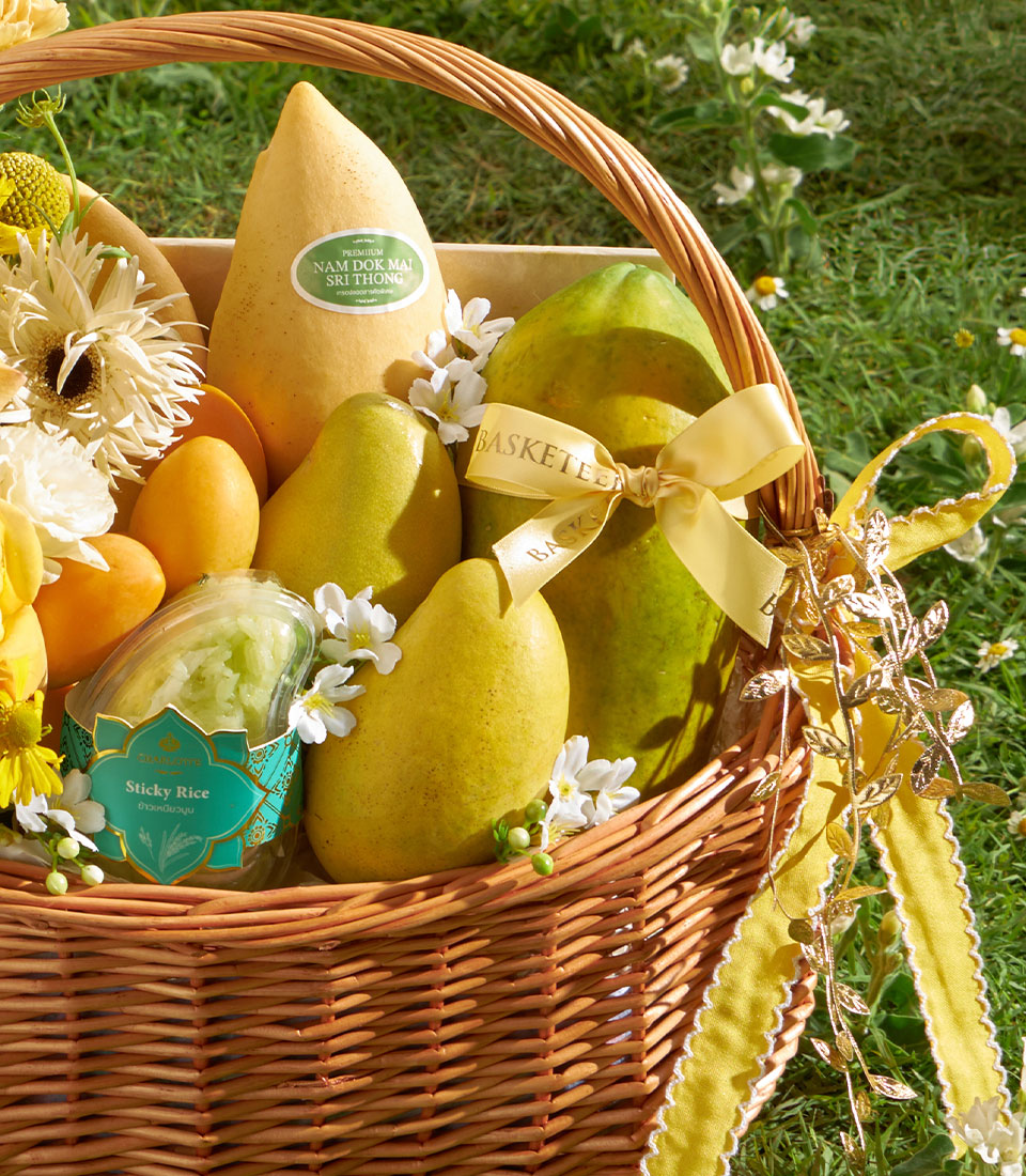 Golden mango gift basket with papaya, sticky rice, and fresh tropical fruit in wicker