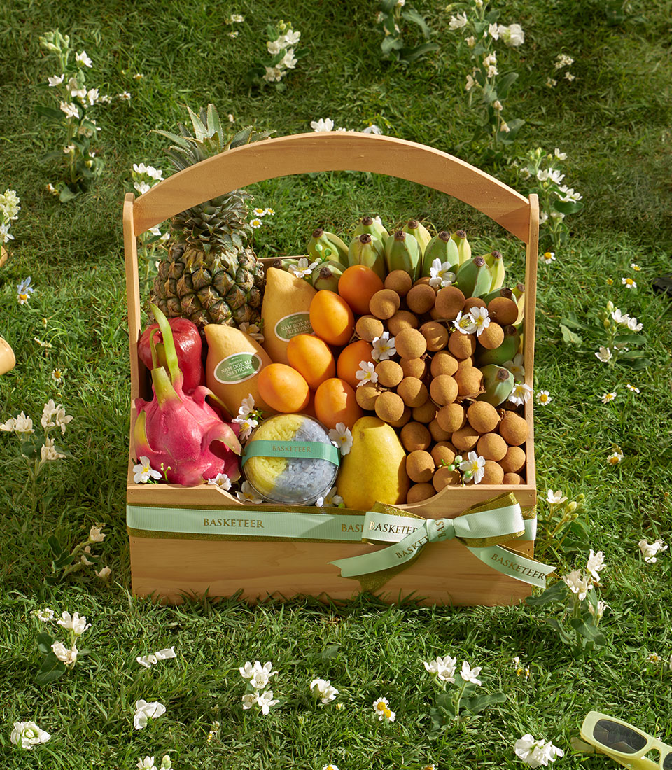 Wooden fruit basket with Thai mangoes, longans, pineapple, bananas, rose apples, dragon fruit, and artisan dessert