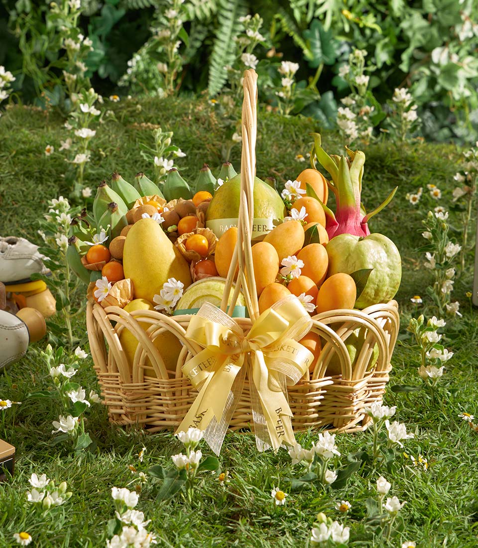 Premium Thai tropical fruit basket with mangoes, bananas, guavas, and citrus in wicker with yellow ribbon