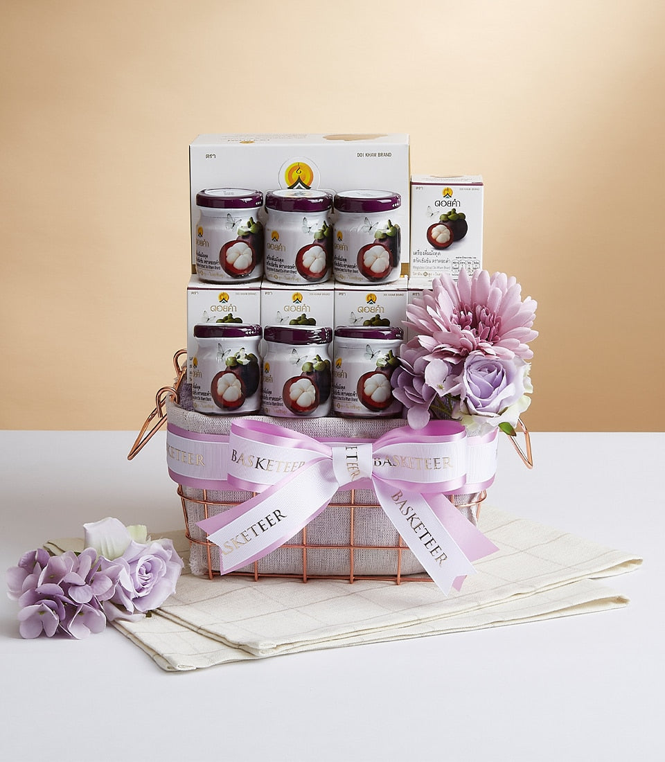 Doi Kham pomegranate extract gift basket with six glass jars, rose gold wire basket, white ribbon bow, and purple artificial
