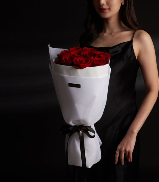 Lush red roses in a romantic bouquet from Flowers by Basketeer. Wrapped in crisp white paper and tied with a black ribbon. Order premium flowers in Bangkok.