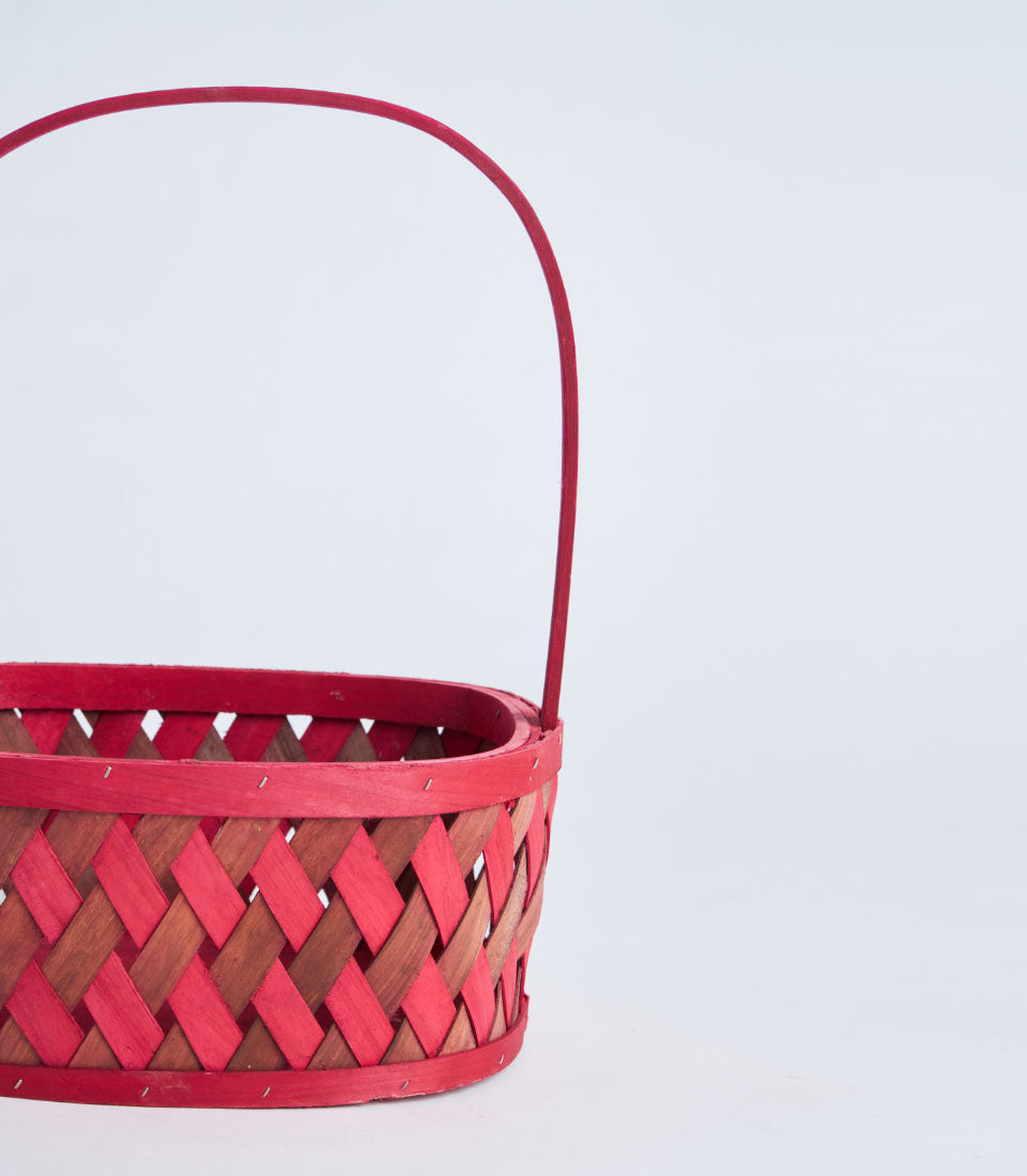 Red woven wooden basket with arched handle, natural and painted striped weave pattern