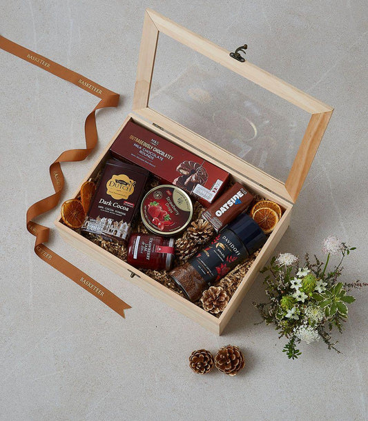 Wooden gift box filled with gourmet treats, chocolate, coffee, jam, and dried citrus accents