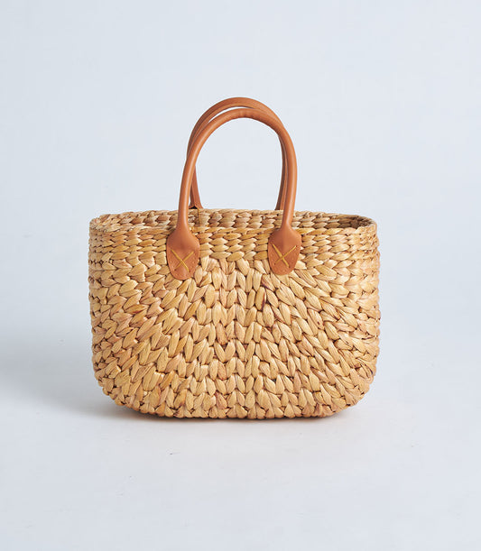 Natural straw tote basket with brown leather handles and woven texture