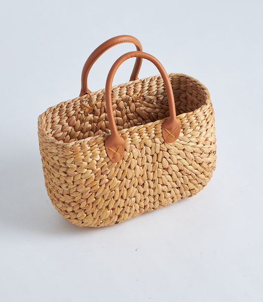 Natural straw basket with curved leather handles, woven artisan design for gifting